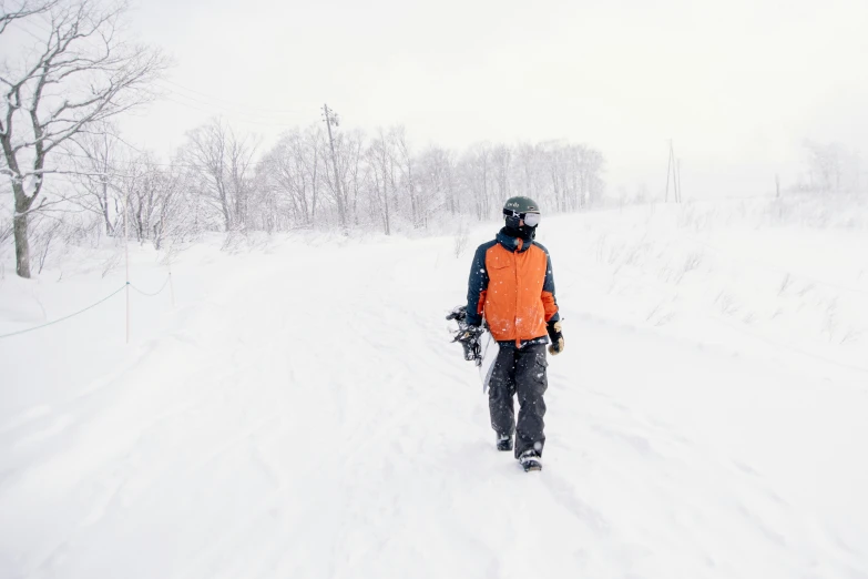 man walking on the snow with a orange vest