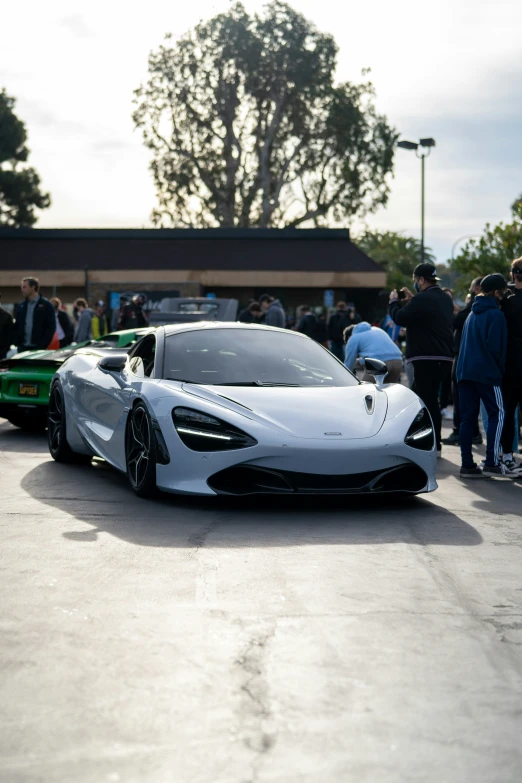 two sports cars in front of a line of people standing near them