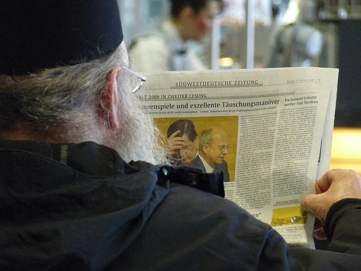 the old man is reading the paper and taking a picture