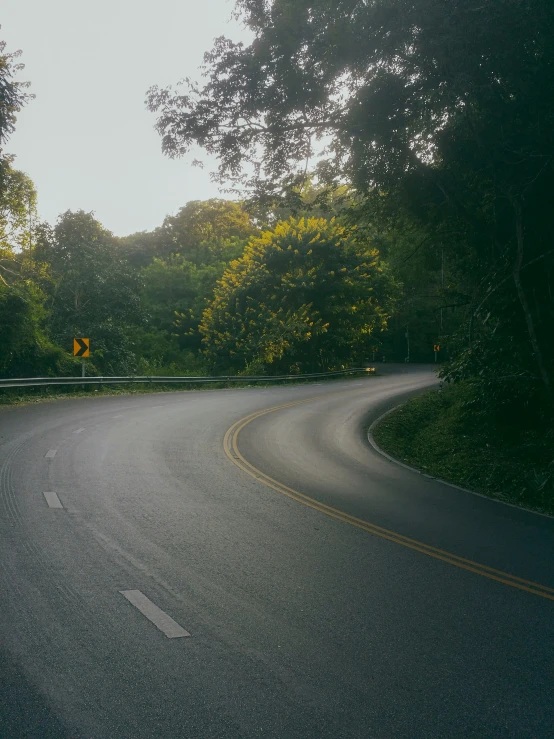 an empty road is shown with some trees in the background