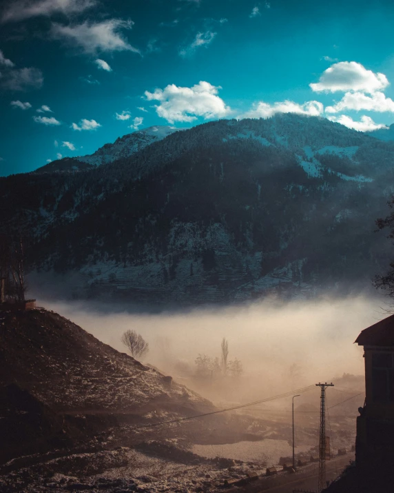 there are mountains and a church tower near some clouds