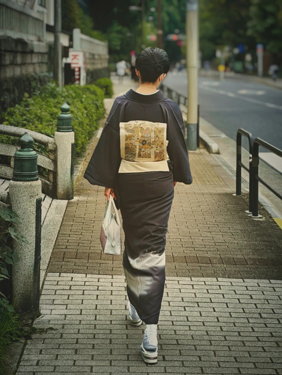 woman walking down the side walk carrying a white bag