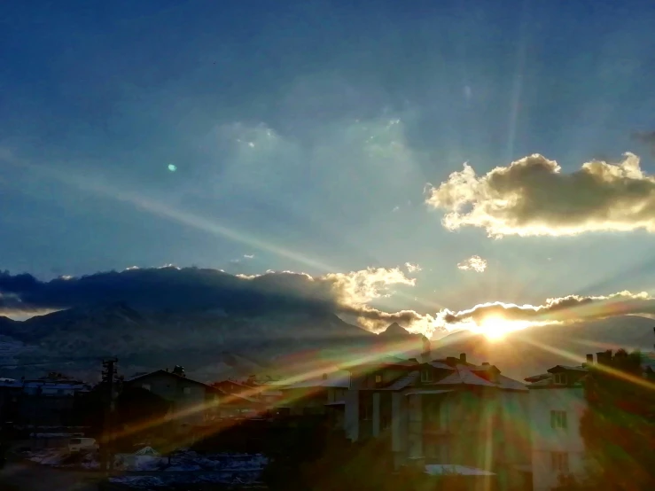 the sun rises above the building and mountains in this pograph