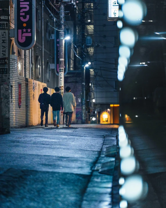 two people walking on a street with a neon sign