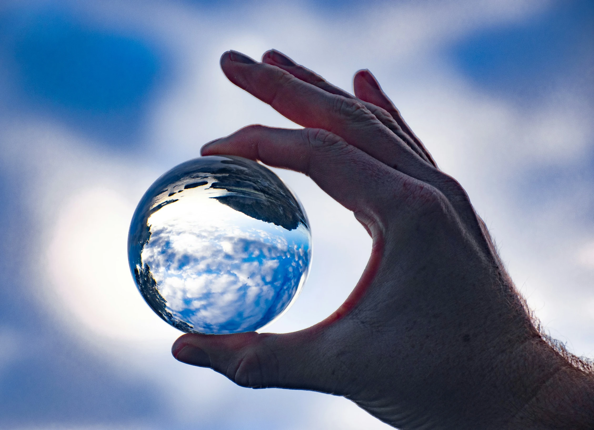 someone holding up the earth outside against the blue sky