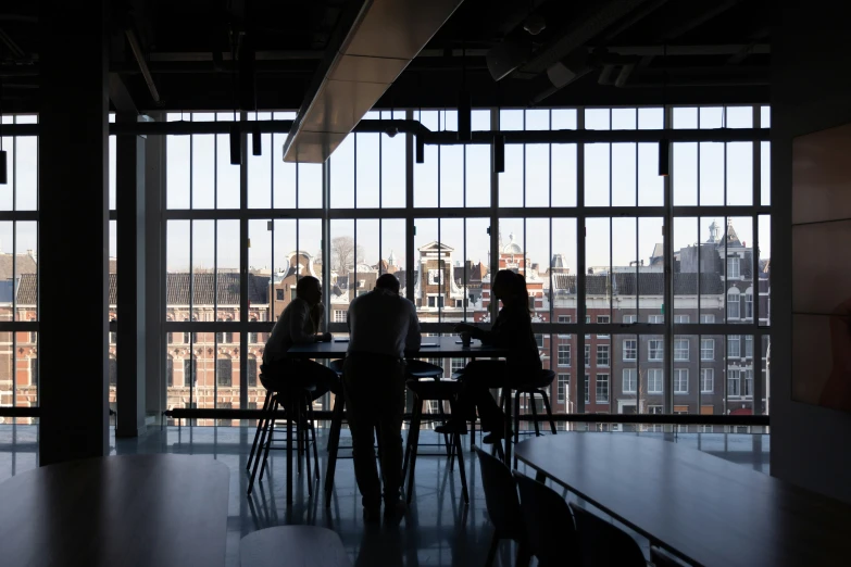 silhouettes of people sitting around a table looking out a window