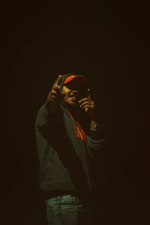 a man standing in the dark with his hands up to his face