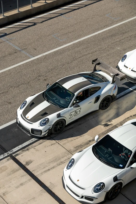 two white sports cars parked side by side on the street