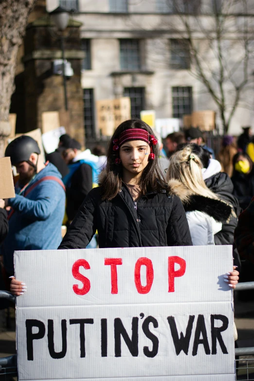 a girl holds a sign saying stop putting's war