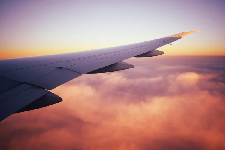 the view from the inside of an airplane showing clouds and bright yellow and purple