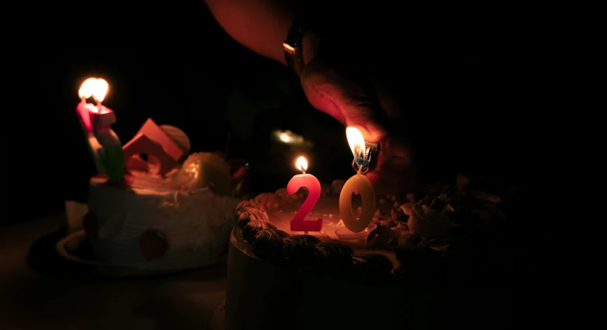 someone lighting candles on a cake with one number