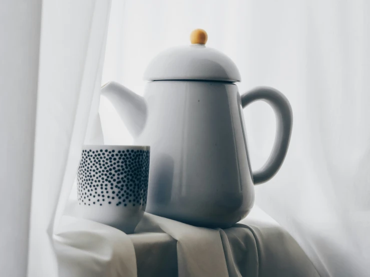 the white tea pot is next to the coffee cup