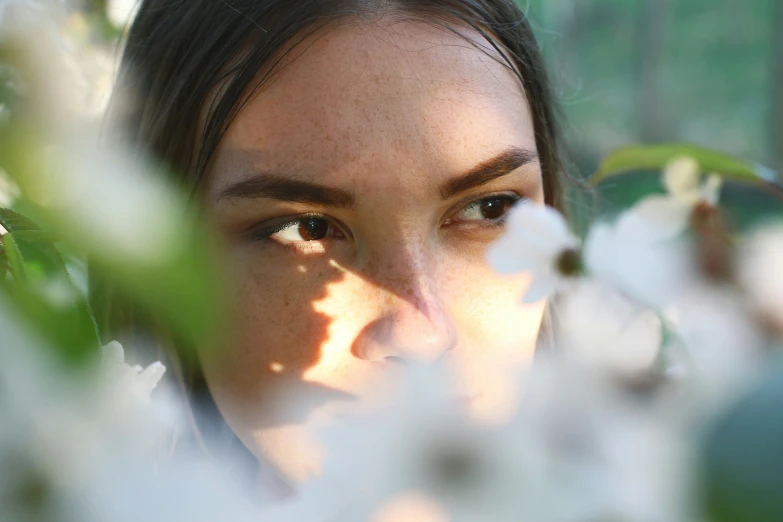 a woman with brown eyes and flowers behind her