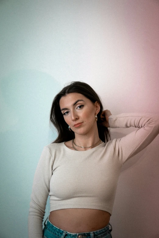 a woman is posing in a white top and blue jeans