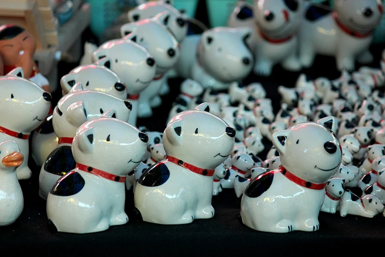 a group of white ceramic puppies that are wearing a red belt