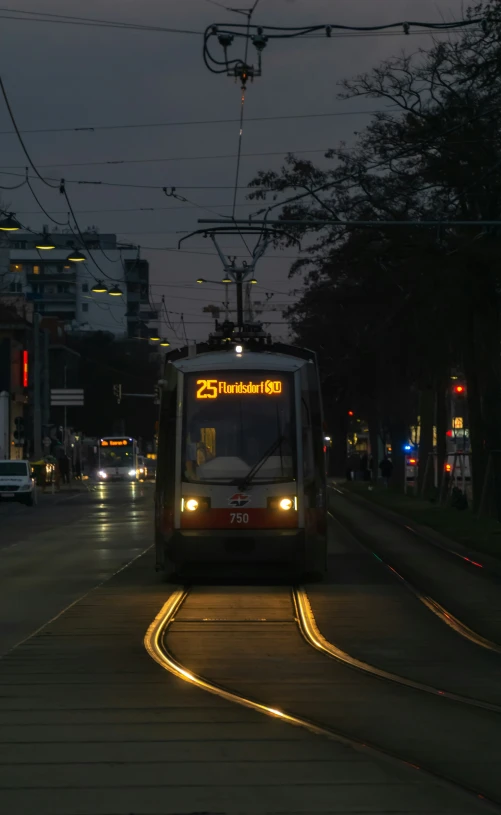 a city bus with lights on driving down the road at night