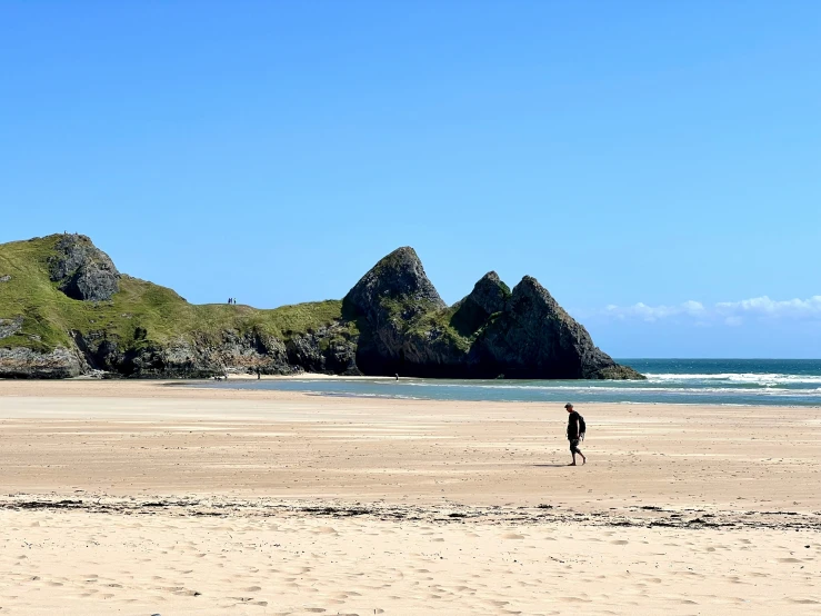 a person walking along a beach near some hills