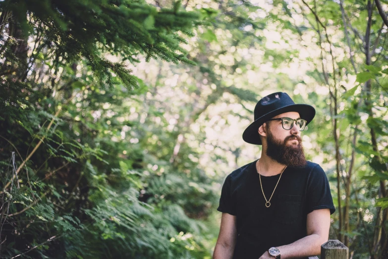 a man with glasses is standing in the woods