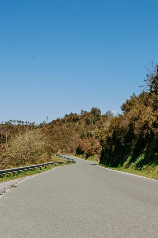 there is a road going by and there are trees on the hill side