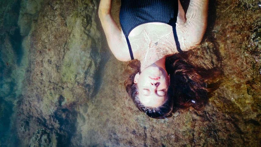 a woman who is laying on the ground with her face partially hidden in the water