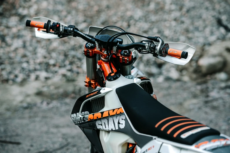 closeup of the front end and handlebars on an orange and black motorcycle