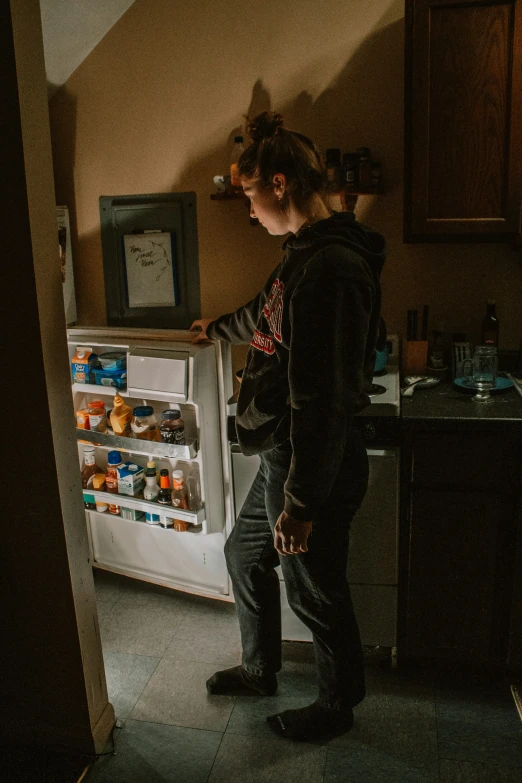 a woman standing in front of an open refrigerator