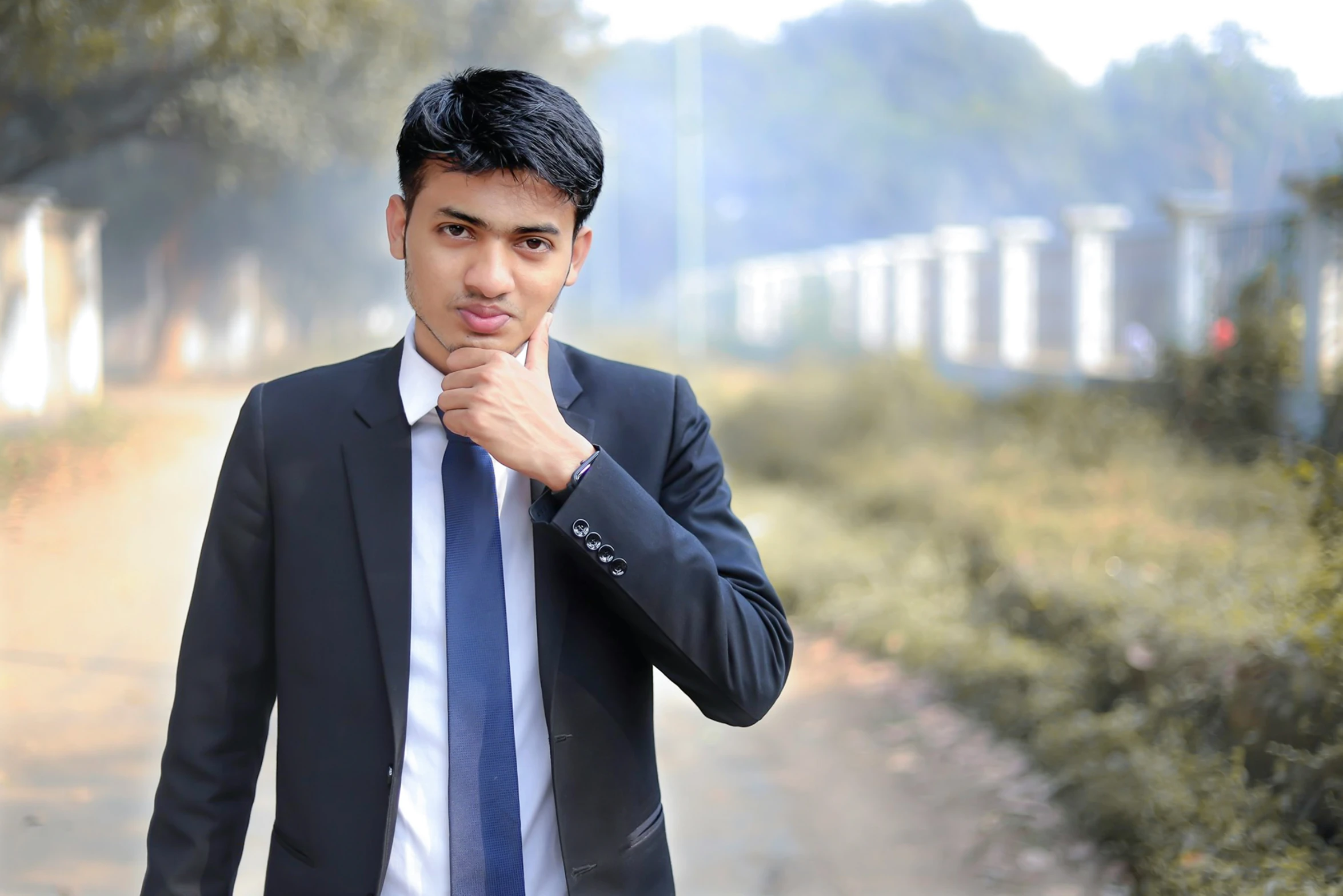 a man in a suit and tie holding his chin on his hand while looking off into the distance