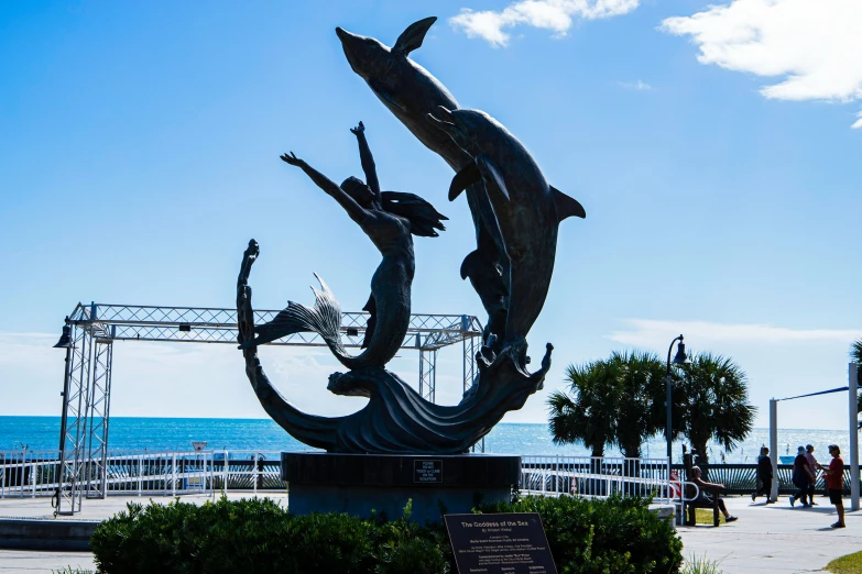 the sculpture of a dolphin is on display next to the ocean