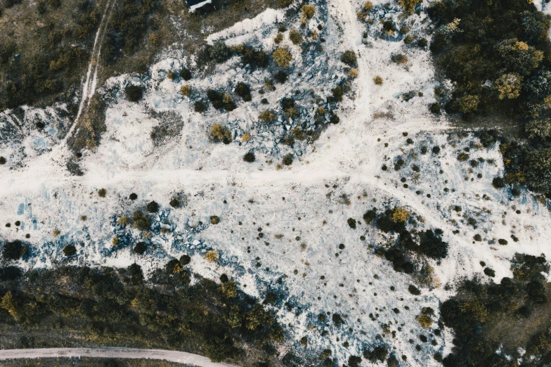 the aerial view of an area where dirt and trees are covered in snow