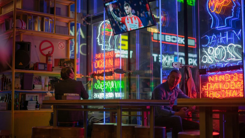 people sitting at the bar with neon lights on the walls