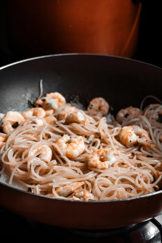 noodles, shrimp and onions in a set on a stove