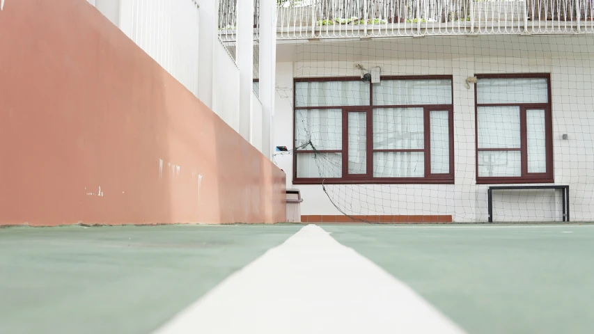 a tennis court with an empty bench and windows