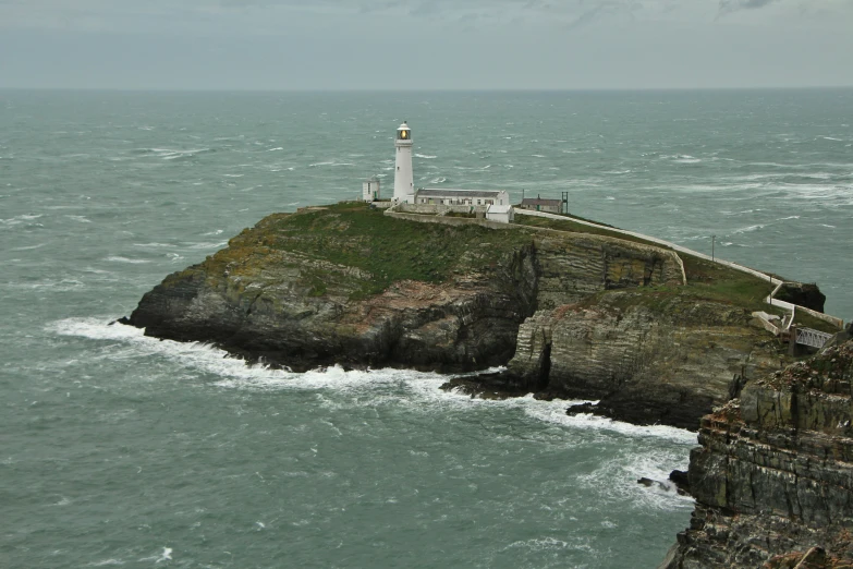 a light house on a rock island with waves crashing around