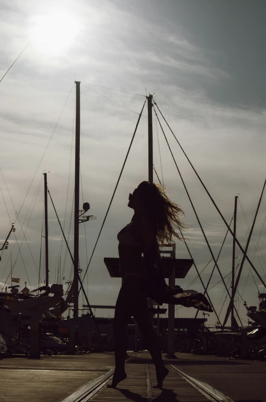 a woman is walking on a dock in front of some boats