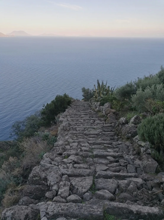 a stone path that runs along a hill over water