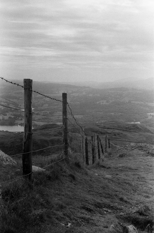 a black and white po of foggy hillside with a fence