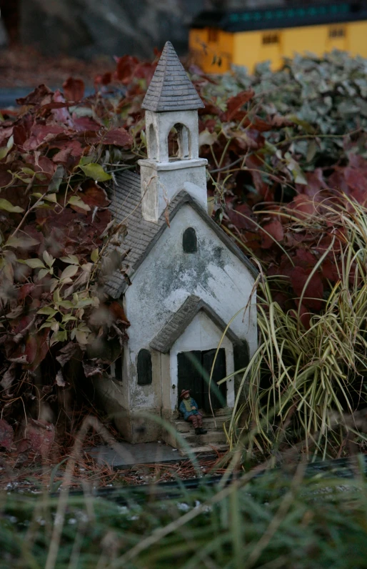 a birdhouse made of cement, placed on a small garden