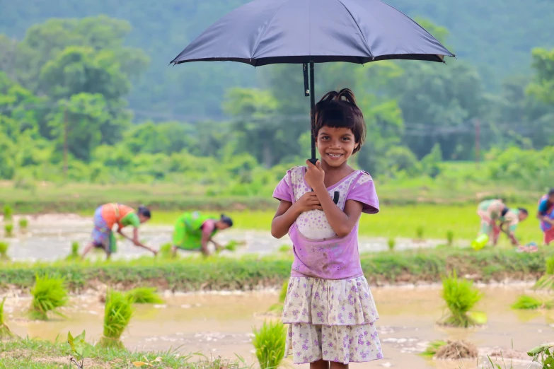  holding umbrella smiling at camera on dirt surface