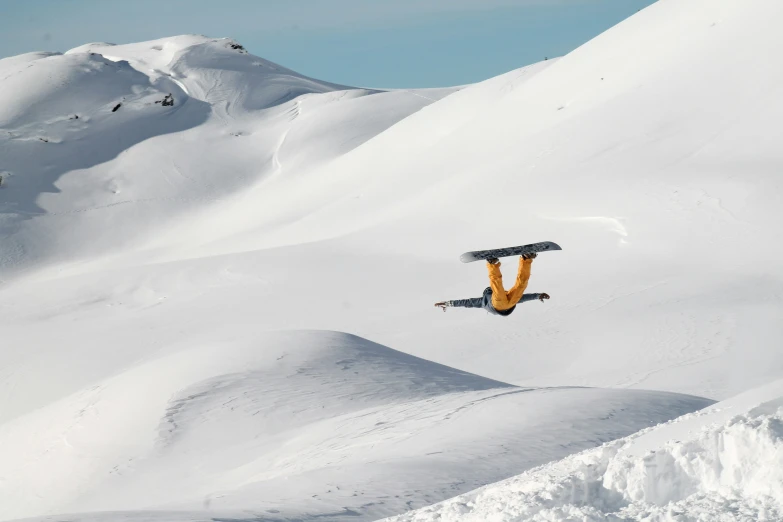 an orange snowboarder in mid air on top of the snow