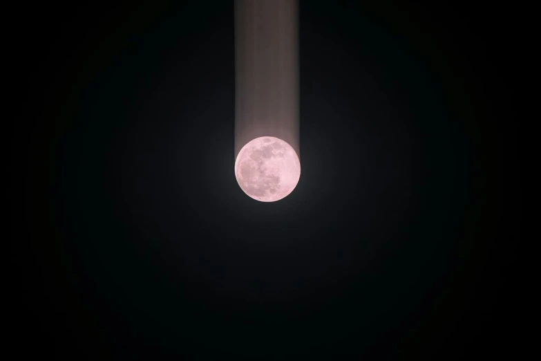 full moon seen from a telescope as it begins to glow pink