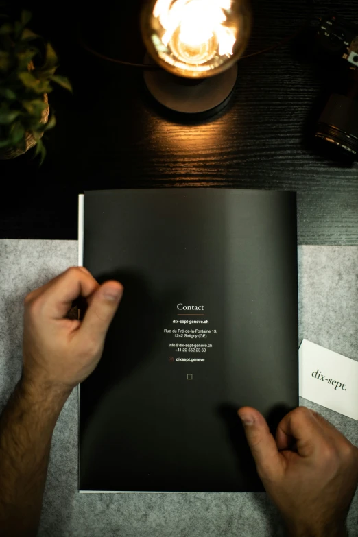 the hand is holding a book above the table