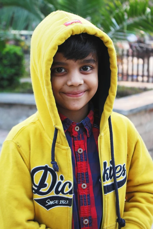 a smiling child wearing a sweatshirt with a hoodie