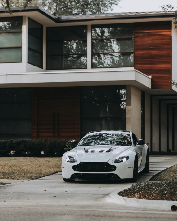 the white sports car parked in front of a very nice house