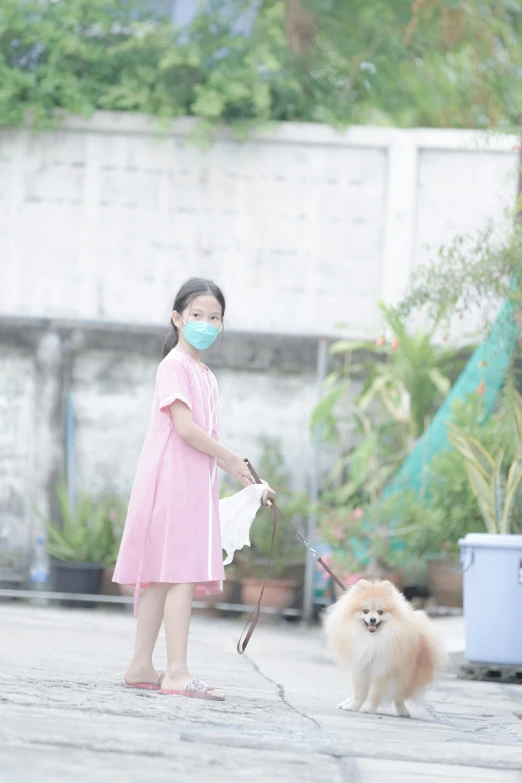 girl holding a small dog while wearing a face mask