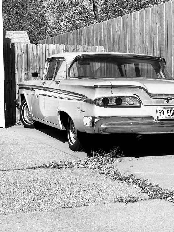 an old car parked in front of a wooden fence