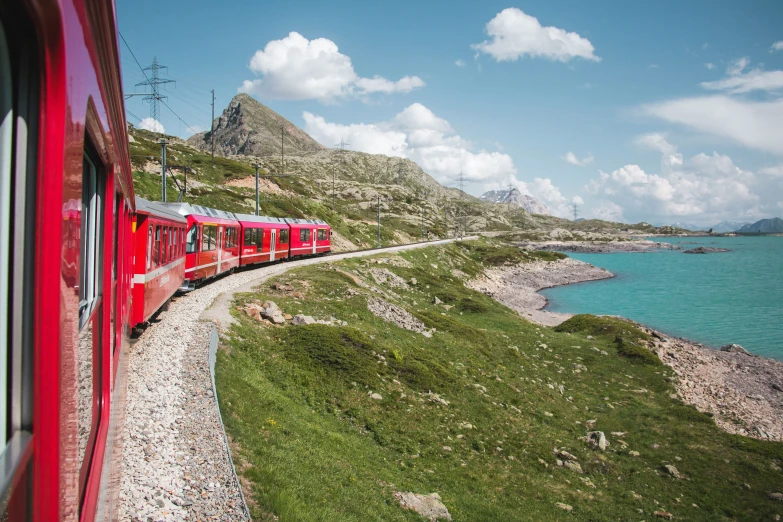 a red train traveling along the side of a cliff