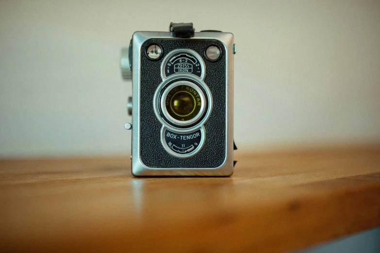 an old camera on a wooden table with a wall in the background