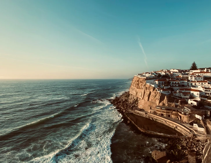 the ocean waves come towards a shore with many buildings on top of it