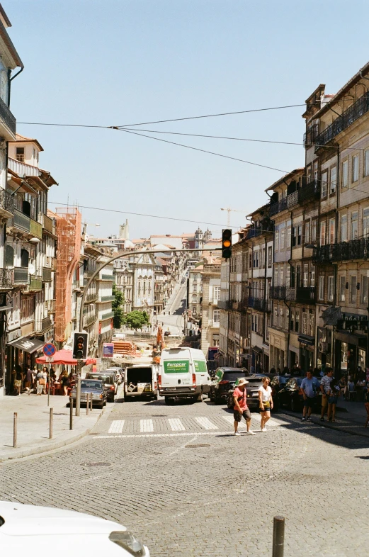 a view down an alley way of several small, old buildings with people and cars