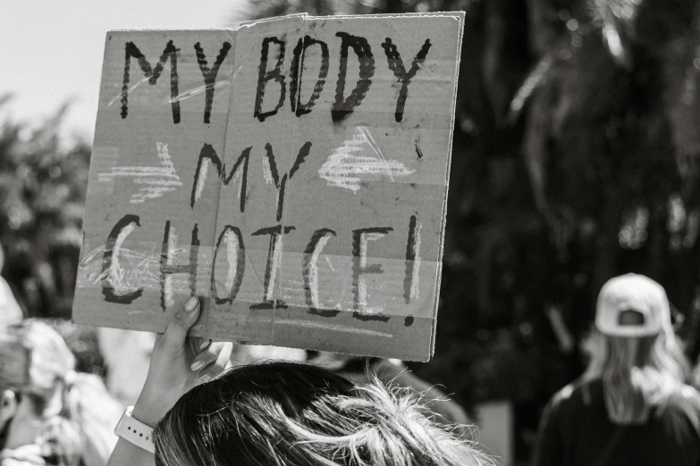 black and white pograph of protestors holding up sign reading, my body, my condo